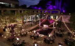 And outdoor courtyard decorated for a night event with rows of lights, tables, and a dance floor.