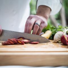 A close up of a chef chopping carrots and other vegetables.