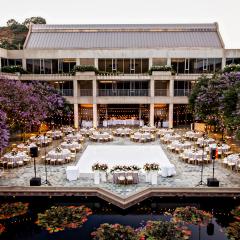An outdoor courtyard with a lily pond decorated with lights, tables, and a dance floor.